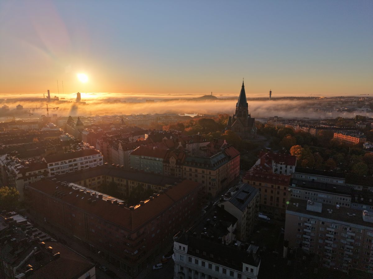 Sofia kyrka och kvarter på Södermalm med dimma och soluppgång i bakgrunden