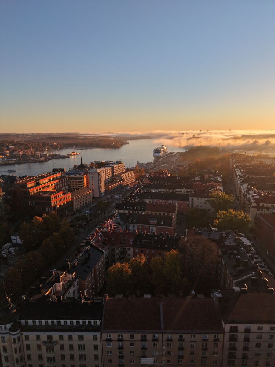 Morgondimma över vattnet och ett kryssningsfartyg vid kajen