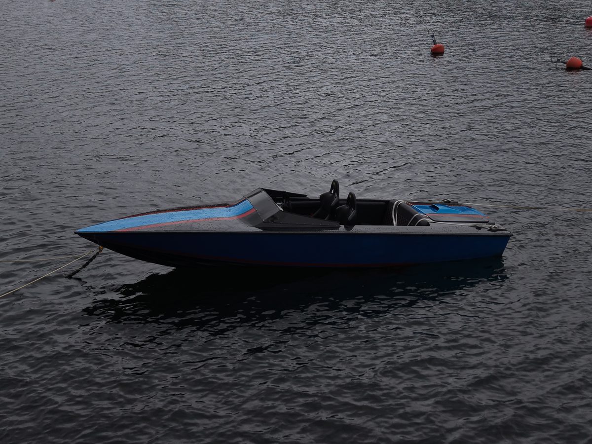 Motorbåt förtöjd på mörkt, stilla vatten