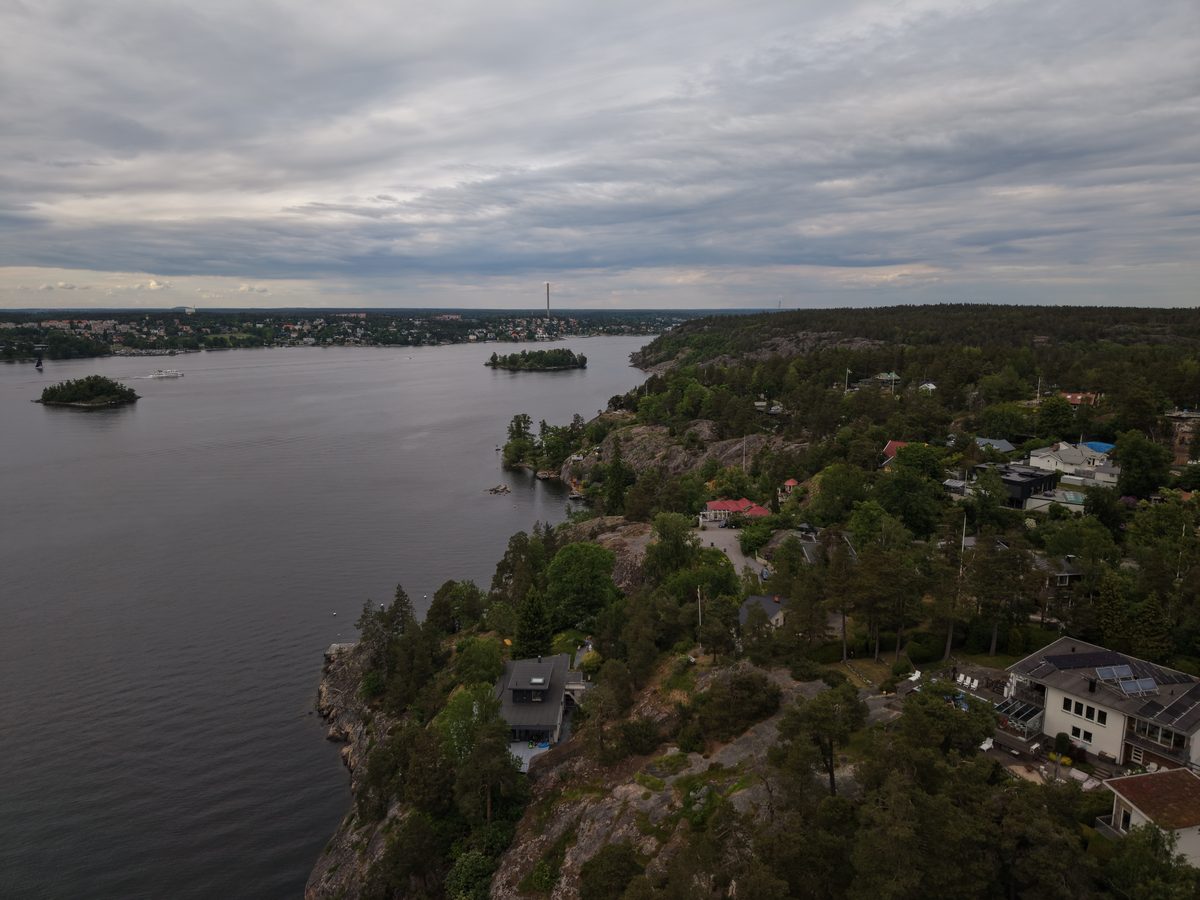 Skärgårdsvik med hus bland träden under grå himmel