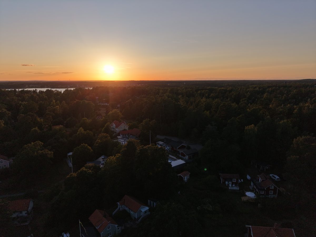 Solnedgång över skog och bebyggelse