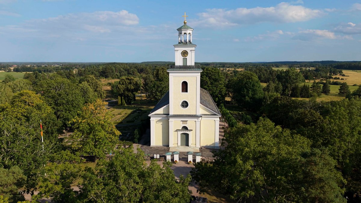 Vit kyrka omgiven av grönska, fotograferad från luften